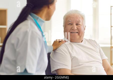 Die Ärztin besucht ihren älteren Patienten zu Hause und unterstützt ihn und spricht mit ihm. Stockfoto