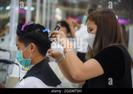 Nonthaburi, Thailand. September 2021. Chalachol Friseursalon, der an einem Kunden arbeitet, während die thailändische Regierung die Sperre teilweise aufhebt, sodass einige Unternehmen wieder öffnen können, indem sie Bedingungen wie soziale Distanzierung und das Tragen von Schutzmasken befolgen. Kredit: SOPA Images Limited/Alamy Live Nachrichten Stockfoto