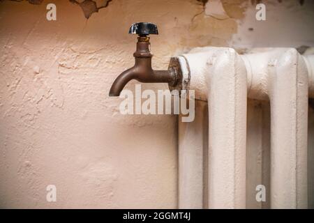 Wasserhahn zum Ablassen von Wasser auf einer alten gusseisernen Dampfheizung Batterie Stockfoto