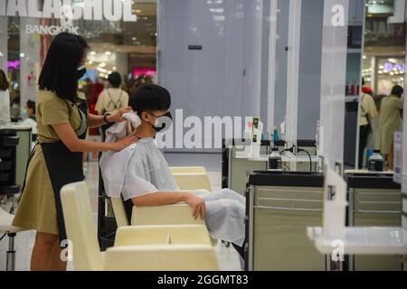 Nonthaburi, Thailand. September 2021. Chalachol Friseursalon, der an einem Kunden arbeitet, während die thailändische Regierung die Sperre teilweise aufhebt, sodass einige Unternehmen wieder öffnen können, indem sie Bedingungen wie soziale Distanzierung und das Tragen von Schutzmasken befolgen. (Foto: Yuttachai Kongprasert/SOPA IMA/Sipa USA) Quelle: SIPA USA/Alamy Live News Stockfoto