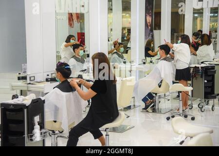 Nonthaburi, Thailand. September 2021. Chalachol Salonbarbiere, die an Kunden arbeiten, während die thailändische Regierung die Sperre teilweise aufhebt, sodass einige Unternehmen wieder öffnen können, indem sie Bedingungen wie soziale Distanzierung und das Tragen von Schutzmasken befolgen. (Foto: Yuttachai Kongprasert/SOPA IMA/Sipa USA) Quelle: SIPA USA/Alamy Live News Stockfoto
