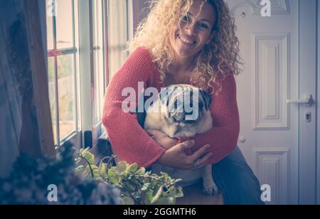 Frau und Hund Home Portrait sitzen zusammen umarmen und genießen Freundschaft zusammen - Lächeln Frau und alte Pug umarmen und vor der Kamera in indo Stockfoto