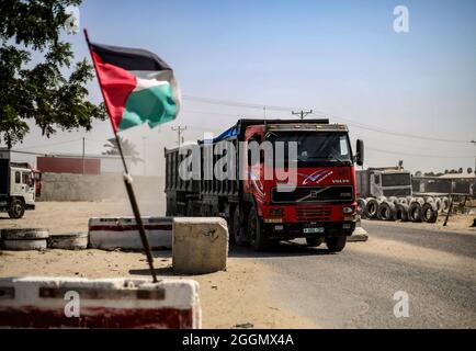 Gaza, Palästina. September 2021. Eine palästinensische Flagge, die mit einem Lastwagen mit Waren im Hintergrund am Güterübergang Kerem Shalom winkt, als Israel eine Reihe von Maßnahmen zur Lockerung der Blockade des Gazastreifens genehmigte, einschließlich der Ausweitung der Fischereizone auf 15 Meilen, Öffnung des Grenzübergangs Kerem Shalom, um die Handelsbewegung zwischen Israel und dem Gazastreifen fortzusetzen, Erhöhung der Wasserquote für den Gazastreifen um 5 Millionen Kubikmeter und Erhöhung der Quote der Händler im Gazastreifen, den Grenzübergang Erez im nördlichen Gazastreifen zu überqueren. Kredit: SOPA Images Limited/Alamy Live Nachrichten Stockfoto