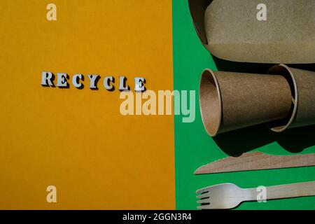 RECYCLING Text Holzgabeln und Pappbecher mit Tellern auf farbigem Hintergrund. Umweltfreundliches Einweggeschirr. Wird in Fast Food, Restaurants, Imbissbuden verwendet Stockfoto