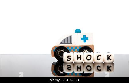 Alphabet Buchstaben mit dem Wort Schock und ein Holzspielzeug Krankenwagen. Weißer Hintergrund. Stockfoto