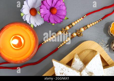 Indisches Festival Raksha bandhan. Rakhi-Thali mit Diya, Blumen und Tilak mit verschiedenen Süßigkeiten wie Gulab Jamun, Kaju katli und Churma Laddo. Stockfoto