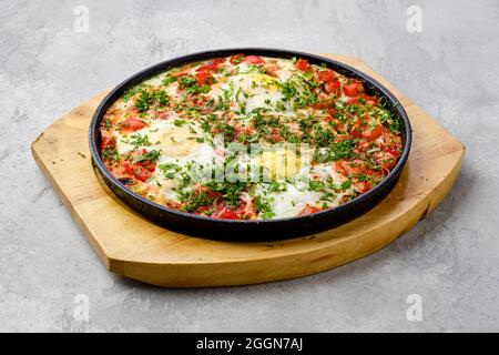 Eier mit Tomate im Ofen in gusseiserner Pfanne gebacken Stockfoto