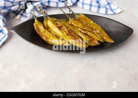 Gefüllte grüne Chilischoten, Bharwa Masala Mirch oder Bharli Mirchi, Sandgi Mirchi. Serviert auf einem schwarzen Teller auf einem hellen Hintergrund. Speicherplatz kopieren. Stockfoto