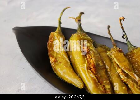 Gefüllte grüne Chilischoten, Bharwa Masala Mirch oder Bharli Mirchi, Sandgi Mirchi. Serviert auf einem schwarzen Teller auf einem hellen Hintergrund. Speicherplatz kopieren. Stockfoto