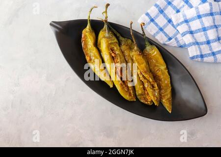 Gefüllte grüne Chilischoten, Bharwa Masala Mirch oder Bharli Mirchi, Sandgi Mirchi. Serviert auf einem schwarzen Teller auf einem hellen Hintergrund. Speicherplatz kopieren. Stockfoto