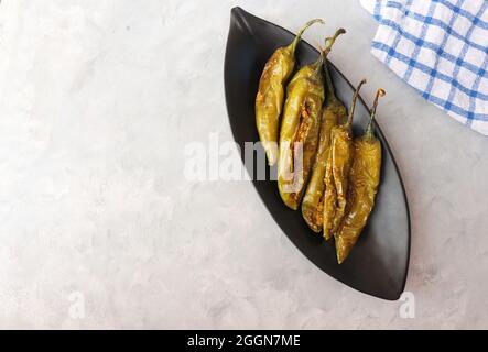 Gefüllte grüne Chilischoten, Bharwa Masala Mirch oder Bharli Mirchi, Sandgi Mirchi. Serviert auf einem schwarzen Teller auf einem hellen Hintergrund. Speicherplatz kopieren. Stockfoto