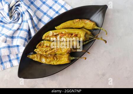 Gefüllte grüne Chilischoten, Bharwa Masala Mirch oder Bharli Mirchi, Sandgi Mirchi. Serviert auf einem schwarzen Teller auf einem hellen Hintergrund. Speicherplatz kopieren. Stockfoto