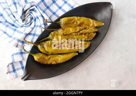 Gefüllte grüne Chilischoten, Bharwa Masala Mirch oder Bharli Mirchi, Sandgi Mirchi. Serviert auf einem schwarzen Teller auf einem hellen Hintergrund. Speicherplatz kopieren. Stockfoto