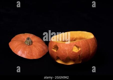 Lächelnder Halloween-Kürbis mit Augen, die aus einem orangefarbenen Kürbis geschnitzt und auf schwarzem Hintergrund isoliert wurden, bereitet Jack-o'-Laterne auf den Urlaub vor Stockfoto