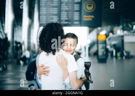 Das junge Familienpaar am Abflugbereich des Flughafens sagte Auf Wiedersehen oder hallo und umarmte sich mit einem Lächeln. Ankunft und Wiedersehen warten auf die Reise Stockfoto