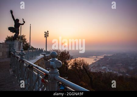 Die Fackellenträger-Skulptur auf dem Gellert-Hügel mit Blick auf Budapest und den Sonnenaufgangshimmel im Hintergrund, Ungarn Stockfoto