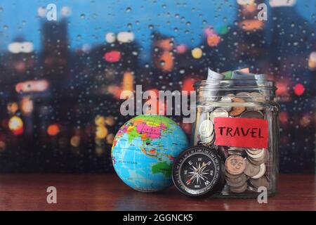 Reisekostenkonzept. Münzen im Glas, Erdkugel und Kompass mit Platz für Text. Stockfoto