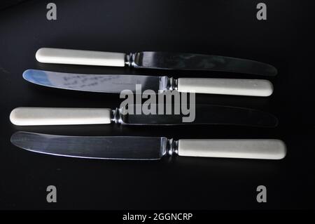 Antike Buttermesser auf schwarzem Hintergrund in einem sich wiederholenden Muster Stockfoto