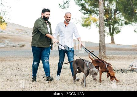 Ein paar glückliche Kinder, die den reinrassigen Hund laufen. Die glückliche lgtb-Familie Stockfoto