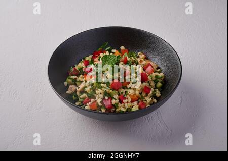 Orientalische traditionelle Salattabbouleh aus Bulgur oder Couscous, Geflügelfleisch, Petersilie, Minze, Zitrone, Tomaten und Pfeffer, Nahaufnahme Stockfoto
