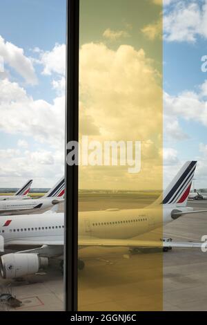 Die Flugzeuge von Air France–KLM Airbus werden auf dem Asphalt am Flughafen Paris CDG in Roissy-en-France, Frankreich, durch buntes Glas gesehen. Stockfoto