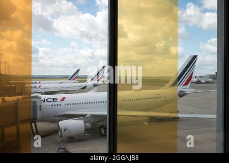 Airbus-Flugzeuge von Air France–KLM werden auf dem Asphalt des Flughafens Paris CDG in Roissy-en-France, Frankreich, in einer Reihe durch buntes Glas gesehen. Stockfoto
