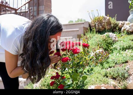 Junge Frau pflegt Rosen im Garten. Selektiver Fokus Stockfoto