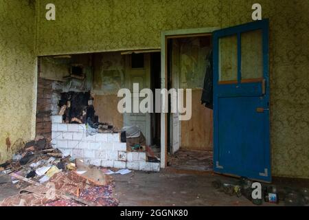 Eine dunkle, schäbige Küche mit dem zerstörten Ofen in einem verfallenen, verlassenen Haus. Stockfoto