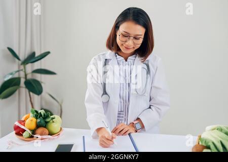 Porträt der Jungen lächelnd weibliche Ernährungsberaterin in der Beratung. Ernährungsberater arbeiten an Diätplan. Stockfoto