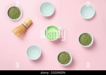 Matcha Latte und Zubehör für die Herstellung auf rosa Hintergrund Stockfoto