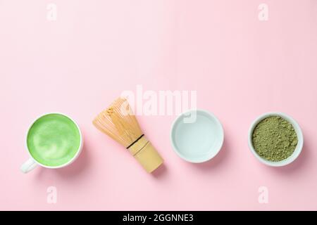 Matcha Latte und Zubehör für die Herstellung auf rosa Hintergrund Stockfoto