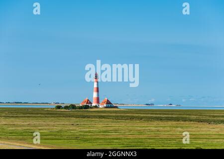 Der Leuchtturm von Westerhever im Wattenmeer an der Nordseeküste, im Hintergrund St. Peter-Ording Stockfoto