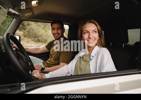 Schönes junges Paar, das auf Beifahrersitzen sitzt und ein Auto fährt Stockfoto