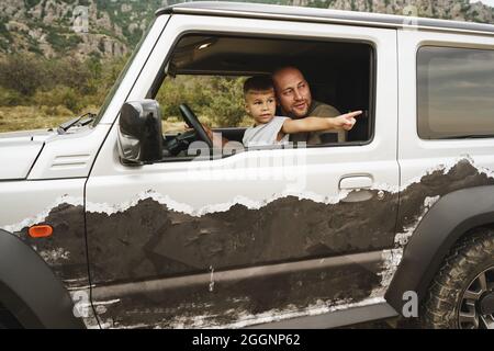 Vater lehrt den kleinen Sohn auf einer Autoreise zu fahren Stockfoto