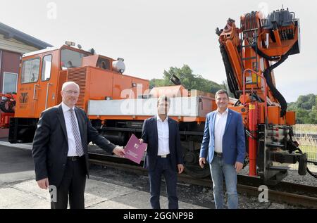 02. September 2021, Mecklenburg-Vorpommern, Bad Doberan: Christian Pegel (SPD) (l-r), Minister für Energie, Infrastruktur und Digitalisierung des Landes Mecklenburg-Vorpommern, überreicht Michael Mißlitz, Geschäftsführer der Mecklenburgischen Bäderbahn Molli, einen Förderbescheid über 662,000 Euro für die Erneuerung der Gleise, Punkte und Signaltechnik vor einem Bauzug, rechts Sebastian Constien (SPD), Landrat des Rostocker Kreises. Das bedeutet, dass der Staat 75 Prozent der Kosten für das Projekt übernimmt. Foto: Bernd Wüstne Stockfoto