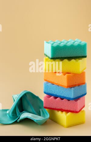 Stapel von bunten Spülschwämmen und Mikrofaser-Servietten auf neutralem beigen Hintergrund, Küchenhaushalt und Reinigungskonzept Stockfoto
