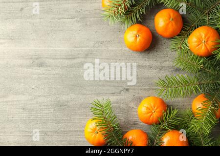 Leckere Mandarinen und Fichtenzweige auf einem grauen Tisch mit Struktur Stockfoto