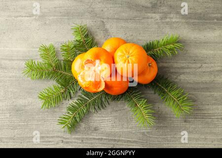 Leckere Mandarinen und Fichtenzweige auf einem grauen Tisch mit Struktur Stockfoto