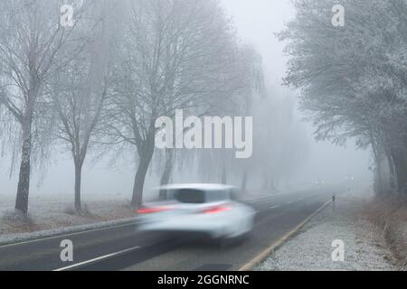 Verschwommenes Auto in Bewegung auf der Straße im Winter während eines nebligen Tages Stockfoto