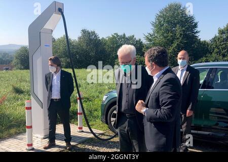 02. September 2021, Baden-Württemberg, Nürtingen: Winfried Kretschmann (Grüne) (2. V.l.), Ministerpräsident von Baden-Württemberg, bei seinem Besuch bei der Firma ADS-tec Energy. Das Unternehmen von Geschäftsführer Thomas Speidel (2. Von rechts) ist auf Schnellladesysteme für Elektroautos spezialisiert. Im Hintergrund wird Kretschmanns Firmenwagen an einer Schnellladestation geladen. Foto: Henning Otte/dpa Stockfoto