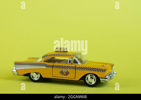 Ein gelbes Spielzeug-Taxi auf einem pastellgelben Hintergrund. Taxi-Service. Stockfoto