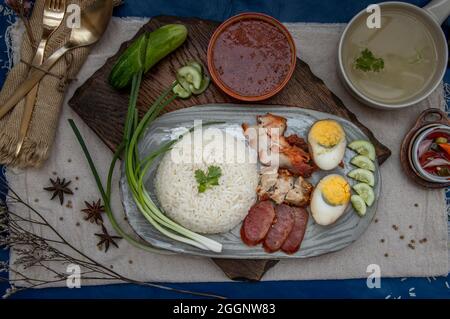 Rotes Schweinefleisch mit Reis (Kao Moo Dang): Rotes Grillpork im thailändischen Stil, Entenei und knuspriger Schweinebauch, geschnittene Gurke mit roter Soße und Brühe. Horizontal Stockfoto