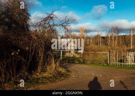 Herbstliche Dorfstraße. Ruhige friedliche Landschaft des Landlebens. Einstöckige Steinhäuser hinter Holzzäunen. Sonniges kaltes Wetter Stockfoto