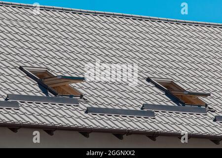 Modernes Design des Daches des Hauses mit offener Fensterarchitektur gegen den blauen Himmel. Stockfoto