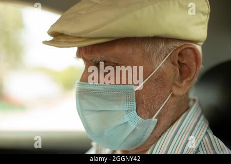 Ein älterer Mann in einem Taxi. Ein alter Mann in einer medizinischen Maske beim Transport. Ein Mann, der 91 Jahre alt ist. Russischer alter Mann. Porträt eines Mannes mit einer Maske auf seinem Stockfoto