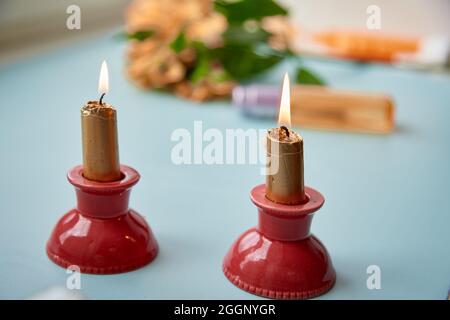 Goldene Kerzen auf rotem Kerzenständer, Gemütlichkeit zu Hause. Hochwertige Fotos Stockfoto