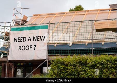 Altes Haus bekommt ein neues Dach. Die Frage „Benötigen Sie ein neues Dach?“ Ist auf einem großen Schild gedruckt. Stockfoto
