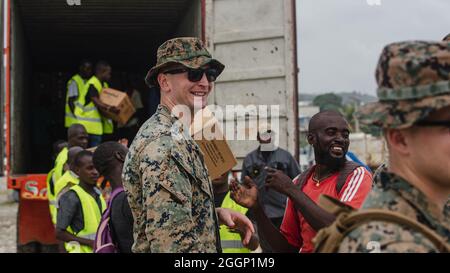 Der US Marine Corps-Kapitän Steven Fleming, geboren in Egg Harbor Township, N.J., und ein Fluglotse mit 1. Bataillon, 6. Marine Regiment, 2d Marine Division, hilft bei der Auslagerung von Boxen für die Umverteilung mit lokalen Freiwilligen in Port of Jeremie, Haiti, 31. August 2021. „Es ist sehr lohnend, hier zu sein und den Bedürftigen Unterstützung zu bieten“, sagte Fleming. Die Marineinfanteristen und Seeleute an Bord der USS Arlington (LPD 24) haben die Joint Task Force Haiti für eine humanitäre Hilfe- und Katastrophenhilfe-Mission unterstützt. „Ich bin so stolz auf das Engagement, das unsere Marineinfanteristen heute bewiesen haben. Fast Stockfoto