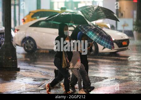 New York, USA. September 2021. Die Menschen laufen im Regen, der durch den Unwetter-Ida verursacht wird, auf einer Straße in New York, USA, 2. September 2021. Kathy Hochul, Gouverneurin des Bundesstaates New York, erklärte am frühen Donnerstag ihren ersten Ausnahmezustand, da die Überreste des Wirbelstromes Ida sintflutartige Regenfälle und schwere Überschwemmungen in die Nordostregion der USA brachten. Quelle: Wang Ying/Xinhua/Alamy Live News Stockfoto