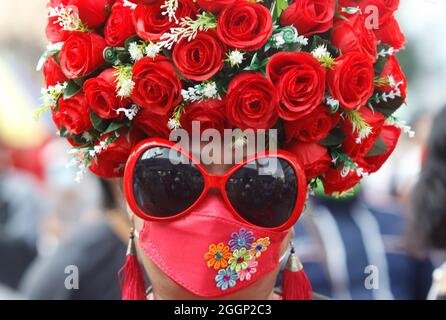 Während der Demonstration wird eine Protesterin mit einer Gesichtsmaske, einer riesigen Sonnenbrille und roten Rosen auf ihrem Kopf gesehen. Demonstranten fordern, dass Thailands Premierminister Prayut Chan-o-cha zurücktritt und die Regierung für ihr grobes Missmanagement der Covid-19-Pandemie zur Verantwortung gezogen wird. Stockfoto